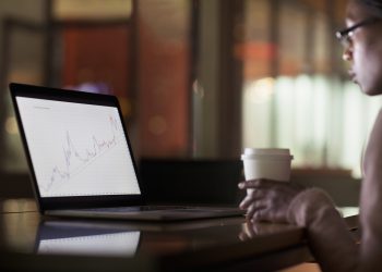 Woman viewing laptop screen with graph diagram