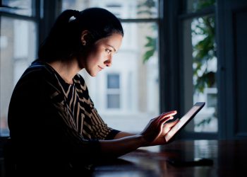 Woman using digital tablet at table.