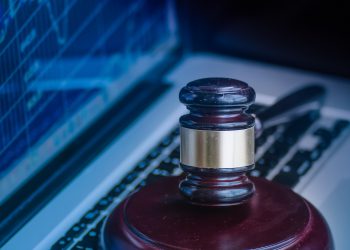 Judges gavel on keyboard with glowing computer screen monitor background.