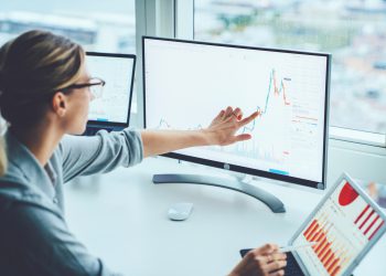 Business woman study financial market to calculate possible risks and profits.Female economist accounting money with statistics graphs pointing on screen of computer at desktop. Quotations on exchange