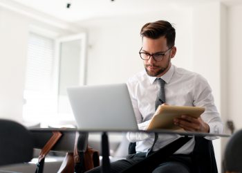 Formally dressed guy is working from home on a laptop.