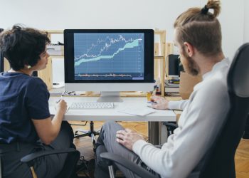 Anonymous businesspeople analyzing a stock market investment graph together in the office